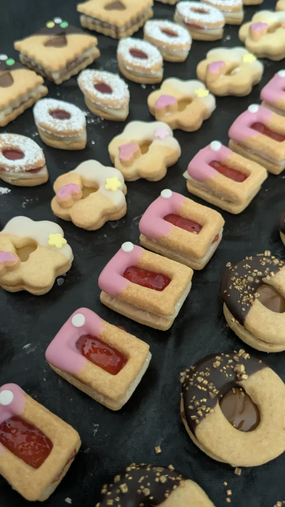 verschiedene helle Plätzchen mit Glasur und Streusel in Reihe gelegt