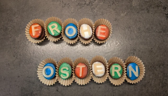 Plätzchen mit Buchstaben aus Zuckergussschrift zusammengelegt zu dem Satz "Frohe Ostern"