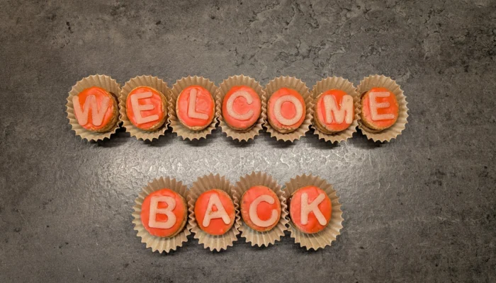 Plätzchen mit Buchstaben aus Zuckergussschrift zusammengelegt zu dem Satz "Welcome Back"